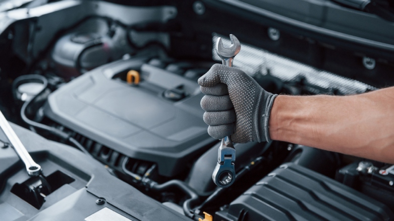Vista cercana de motor con una mano de un mecánico para reparación.