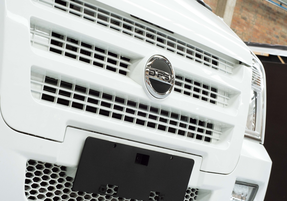 Flota de vans DFSK estacionadas frente a edificio.